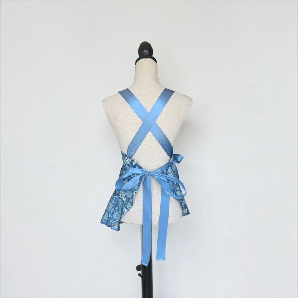 Her Good Eye blue floral kitchen apron with cross-back satin ribbon ties on a mannequin