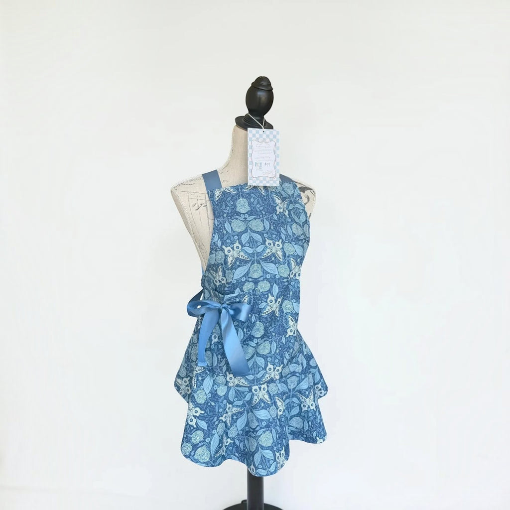 Her Good Eye blue floral print kitchen apron with satin ribbon side bow on a mannequin