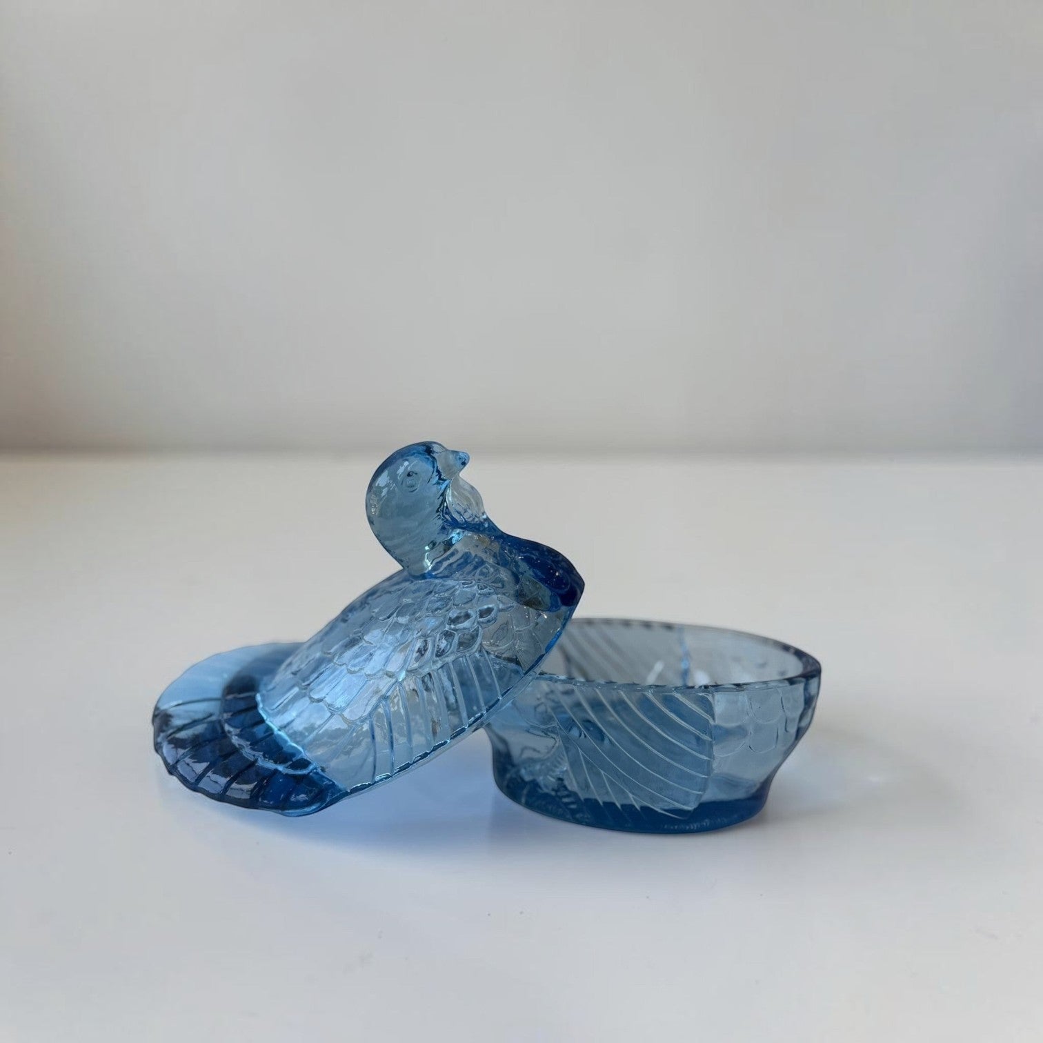 Her Good Eye blue glass bird trinket dish with lid, featuring intricate feather details and a lidded compartment.