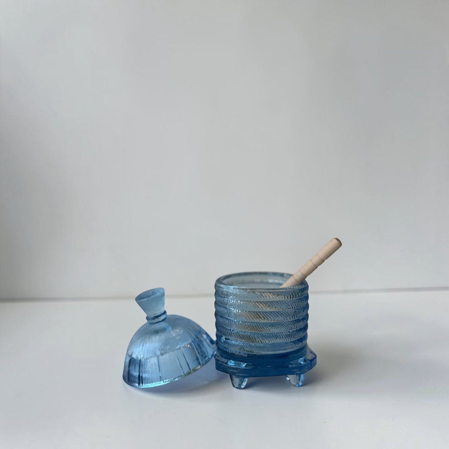Her Good Eye blue glass honey pot with dipper, ribbed beehive design, on four feet.