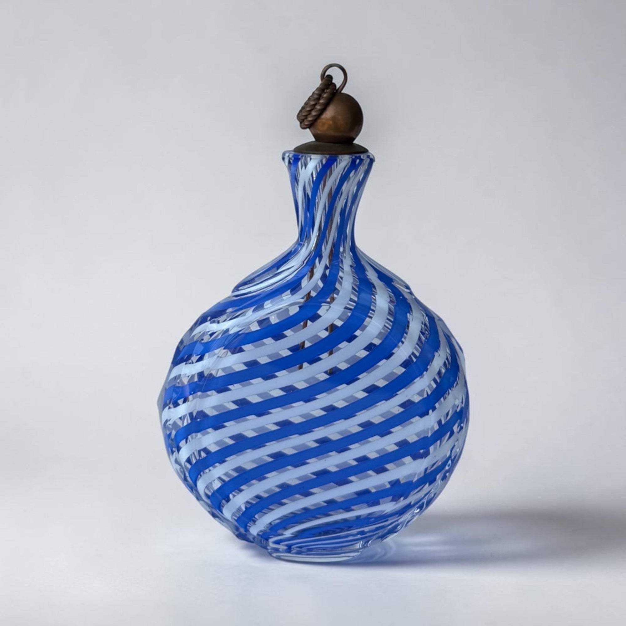 Her Good Eye blue and white swirl glass bottle with copper stopper and rope detail. Murano-style decanter.