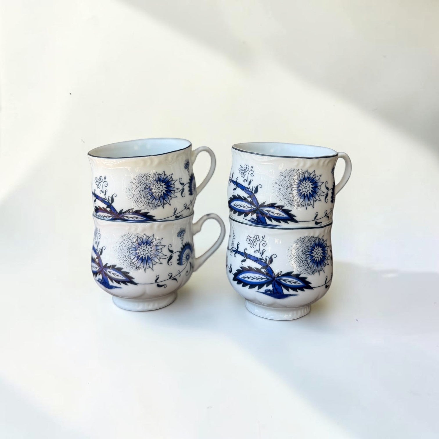 Her Good Eye blue and white floral ceramic teacups with scalloped edges and black trim. Set of 4.