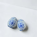 Her Good Eye pair of blue and white porcelain decorative eggs with intricate cut-out floral designs.