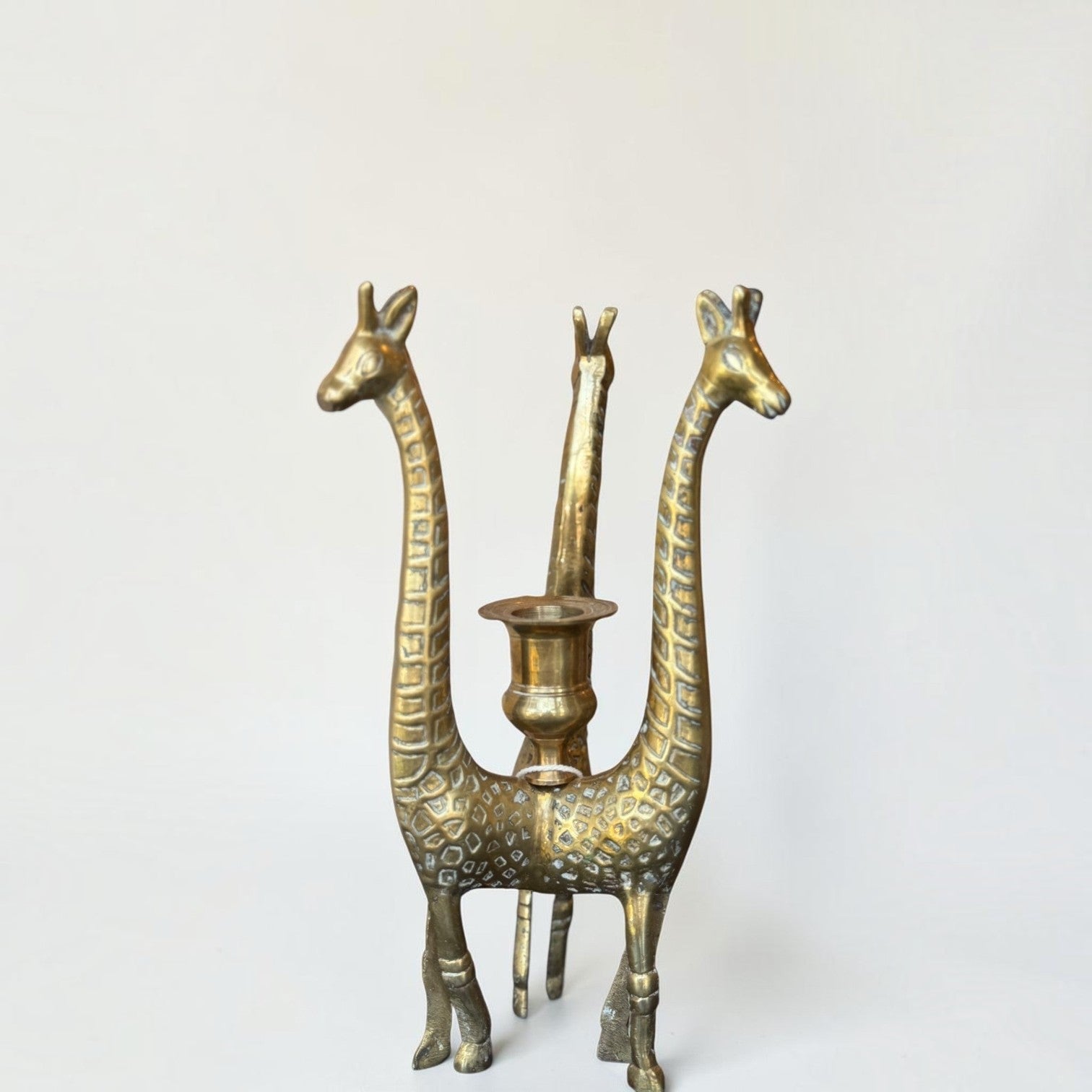 Her Good Eye vintage brass giraffe figural candlestick holder with three giraffes supporting a central candle cup.