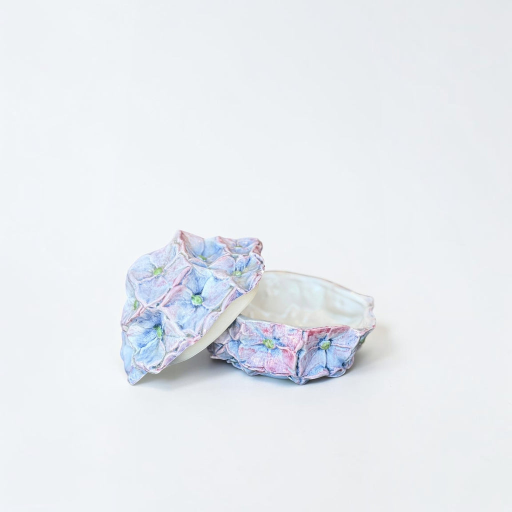 Her Good Eye handcrafted ceramic hydrangea trinket box with pastel blue and pink petal details and a removable lid.