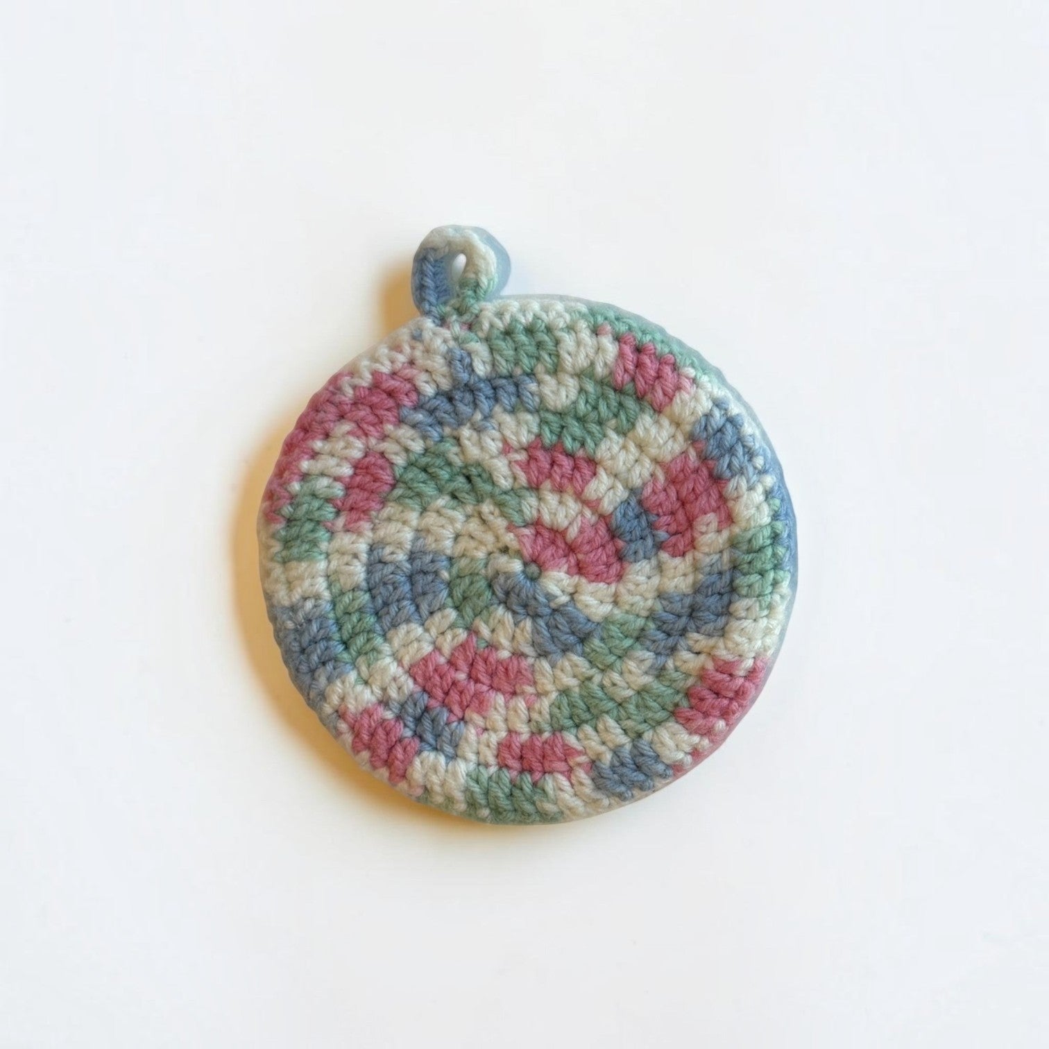 Her Good Eye handmade circular crochet kitchen scrubber in variegated pastel yarn with a convenient hanging loop.