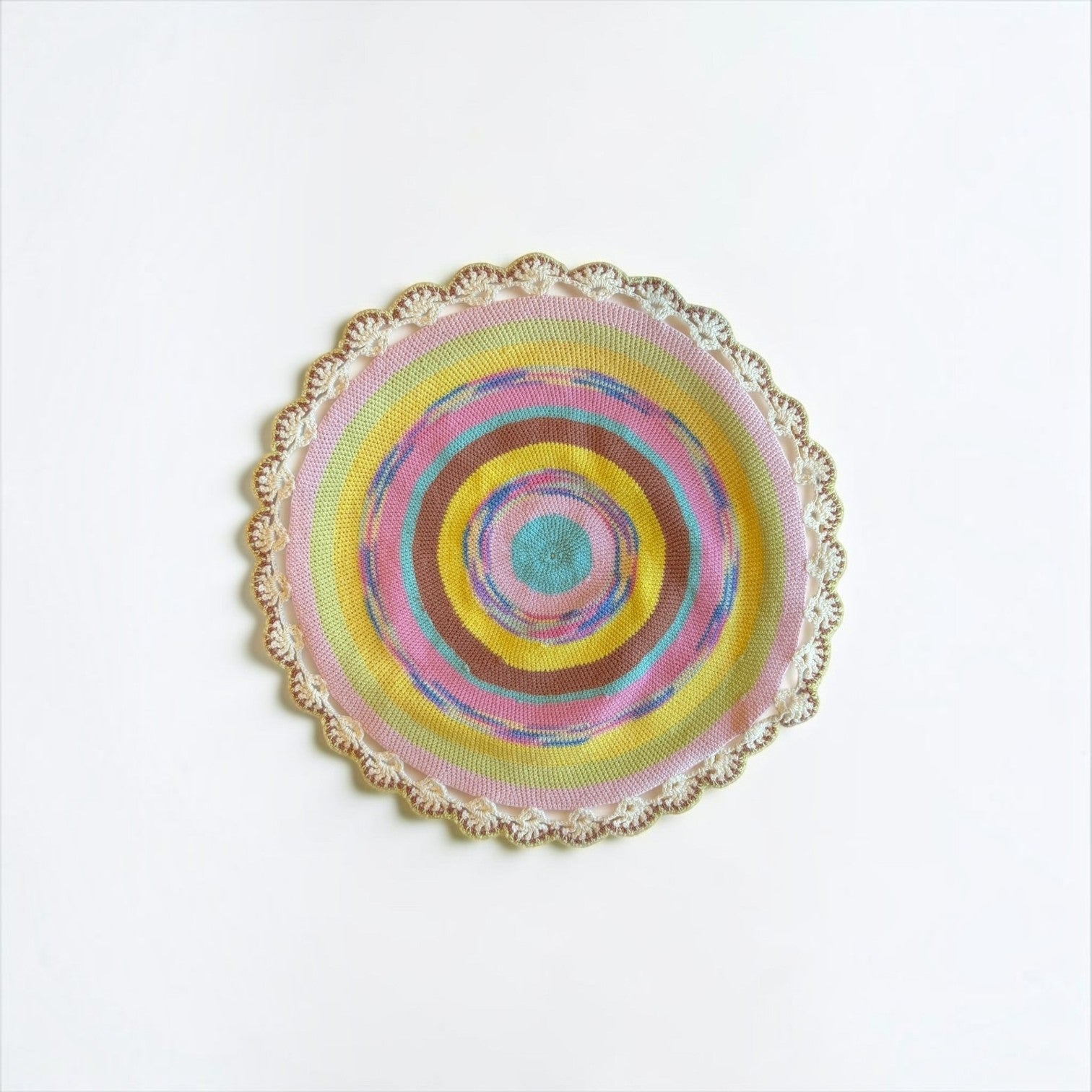 Her Good Eye handmade circular crochet table mat with vibrant concentric rings and a scalloped cream lace border.