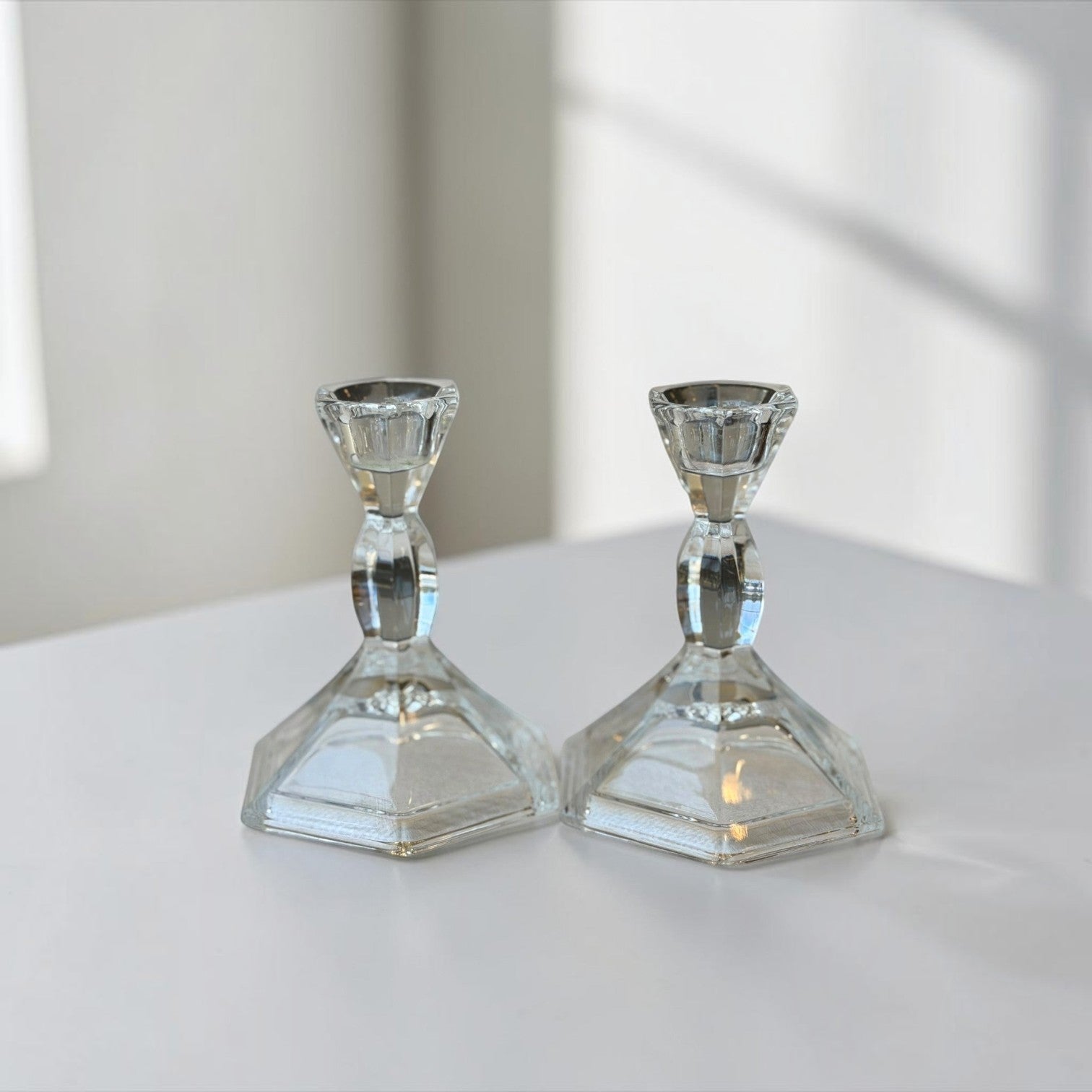 Her Good Eye set of two clear faceted glass candlestick holders with a geometric base for taper candles.