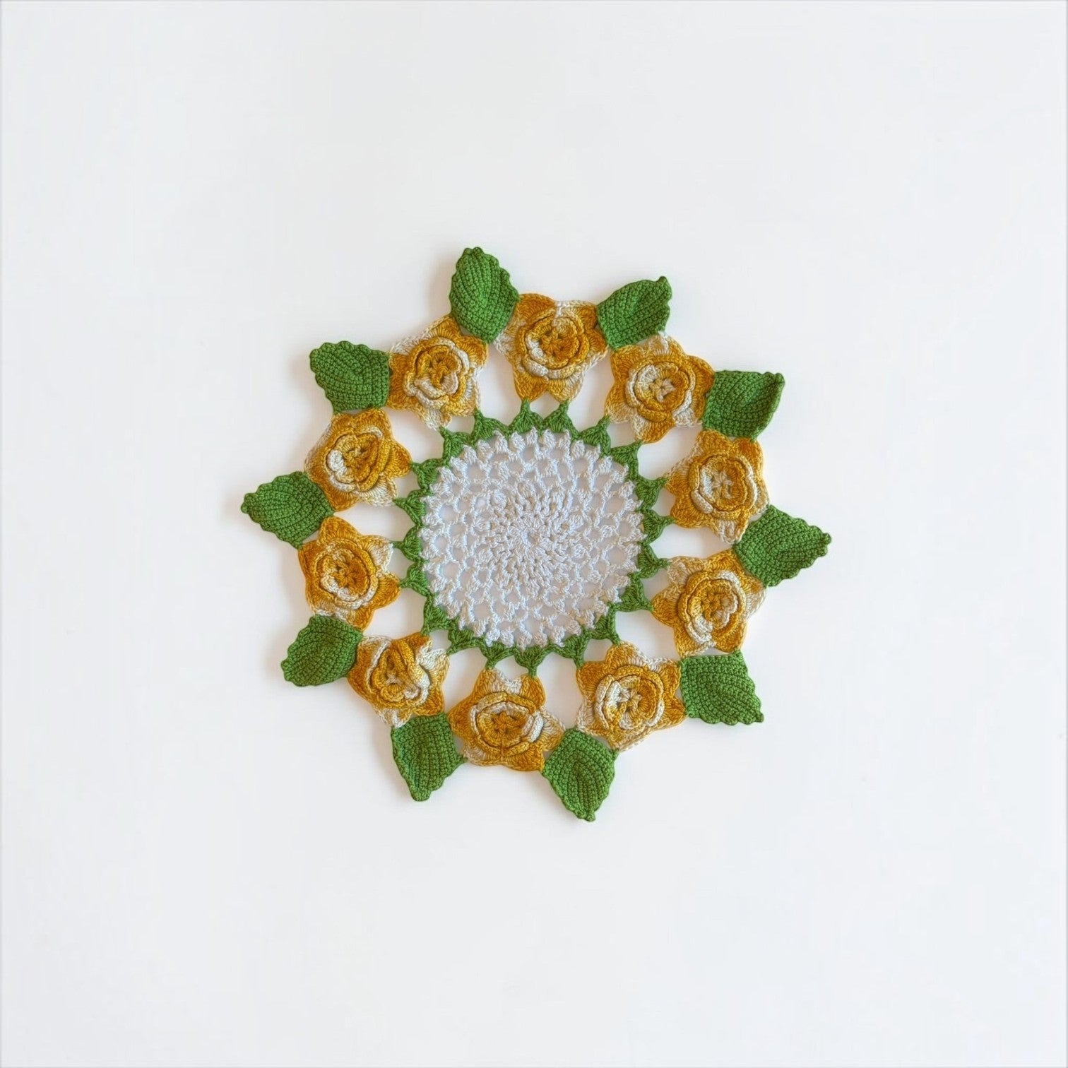 Her Good Eye handmade crochet doily with white center, yellow roses, and green leaves for cottagecore decor.