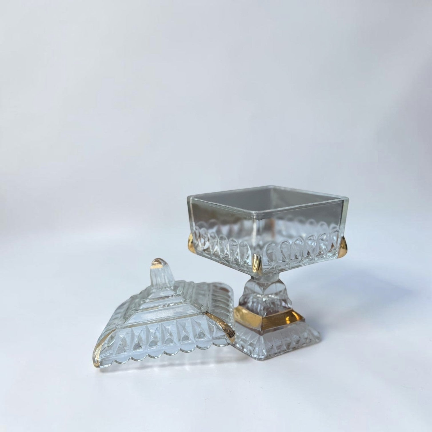 Her Good Eye decorative glass candy dish with lid, featuring diamond-cut pattern and gold accents on a pedestal base.