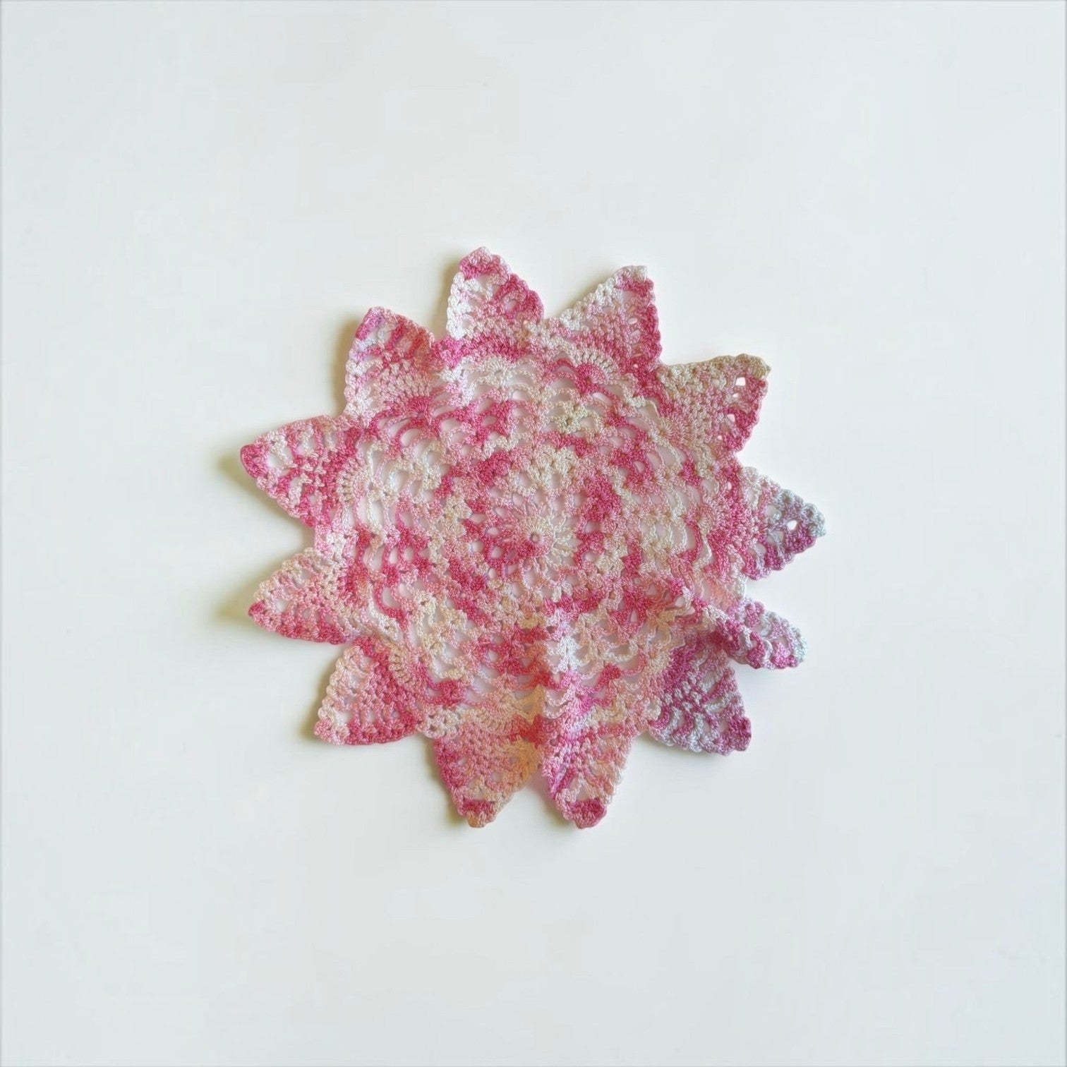 Her Good Eye handmade crochet doily in pink and white with a star-inspired floral pattern for vintage home decor.