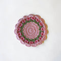 Her Good Eye handmade crochet floral coaster in pastel pink and green with intricate stitch work for cottagecore decor.