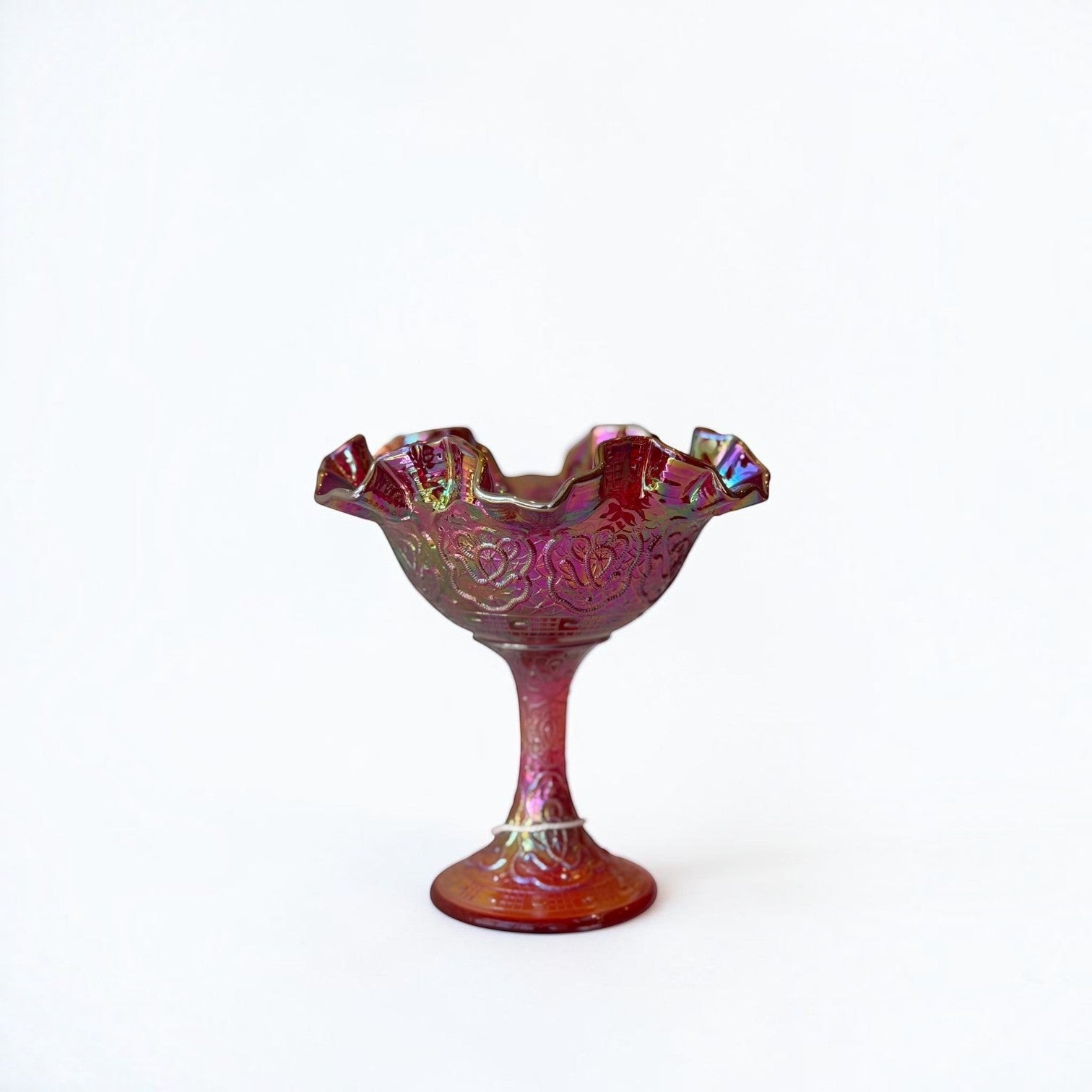 Her Good Eye vintage iridescent ruby red carnival glass pedestal dish with a ruffled edge and embossed floral pattern.