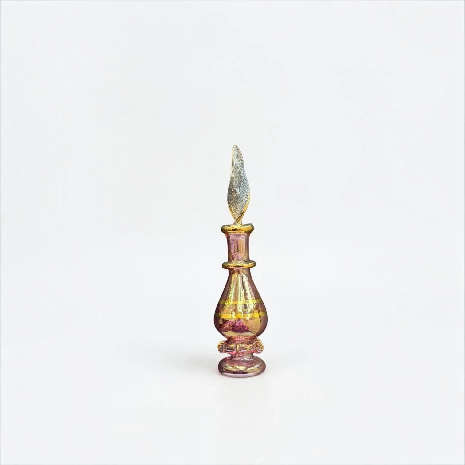 Her Good Eye iridescent glass perfume bottle with gold-tone accents and a unique sculpted stopper on a white background.