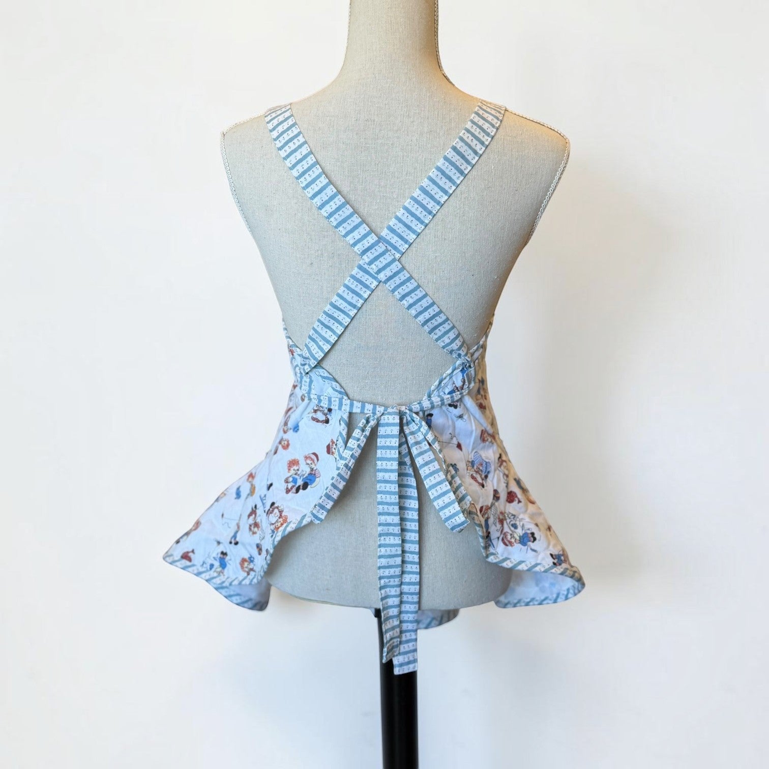 Her Good Eye vintage-inspired quilted kitchen apron with a light blue novelty print and cross-back tie straps.