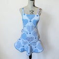 Her Good Eye quilted kitchen apron featuring blue and white heart patchwork, floral patterns, and a ruffled hem.