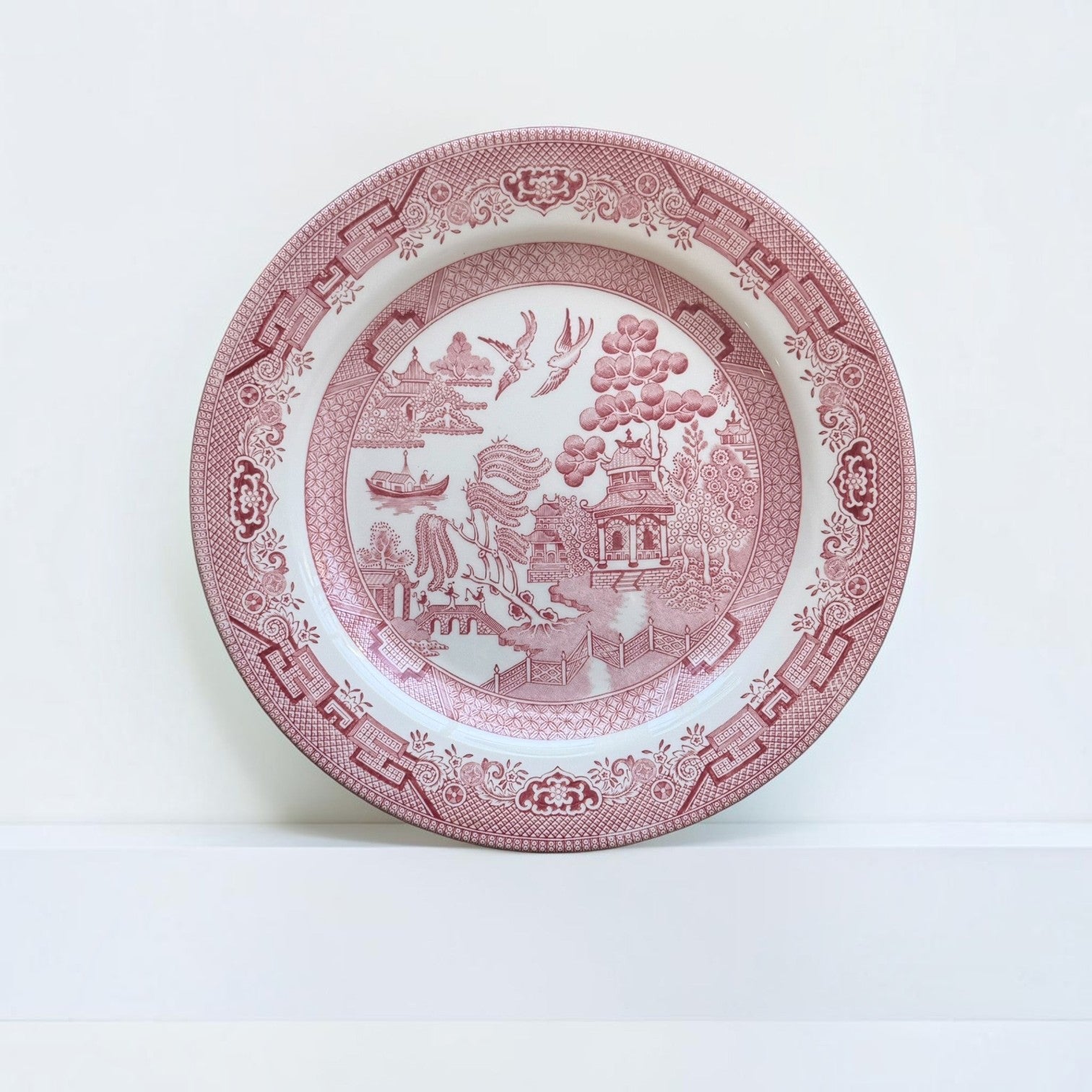 Her Good Eye ceramic dinner plate in red and white with a traditional chinoiserie Willow pattern and geometric rim.