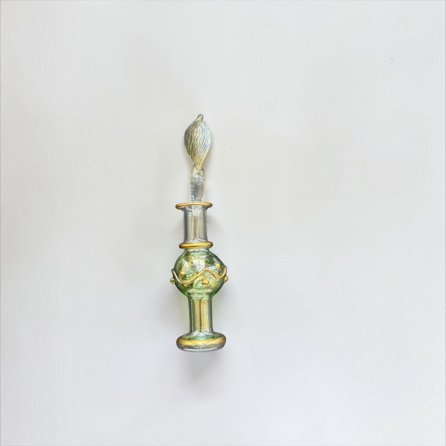Her Good Eye hand blown glass perfume bottle in sage green with gold-tone accents and a decorative glass stopper.