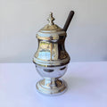 Her Good Eye vintage silver-plated sugar bowl with ribbed base, lid, and a dark serving spoon on a white surface.
