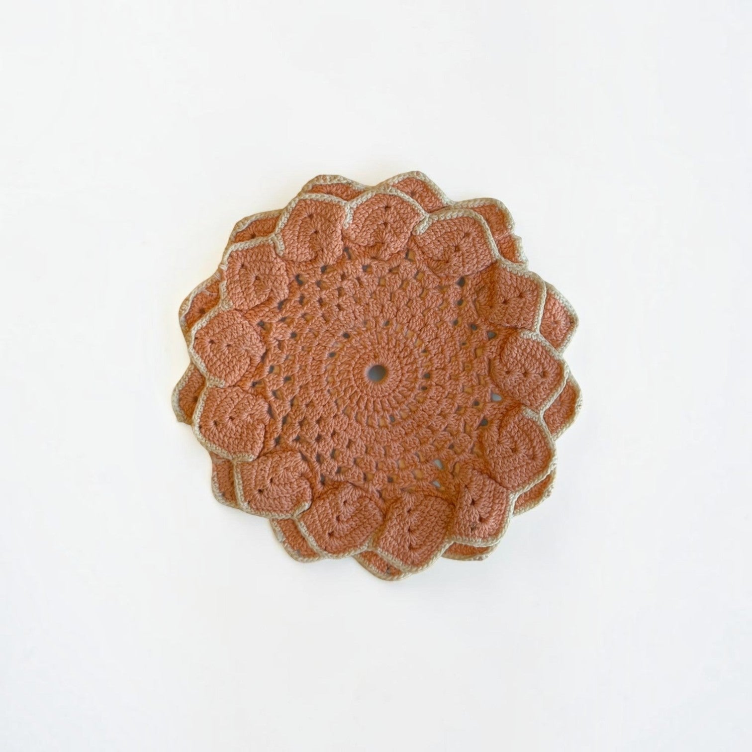 Her Good Eye handmade terracotta crochet table doily with a beige scalloped edge and intricate floral pattern.