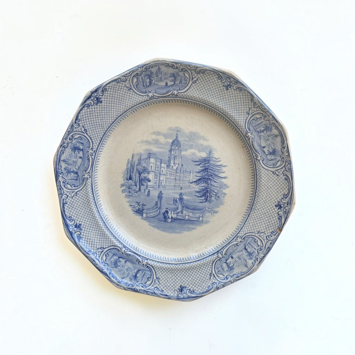 Her Good Eye vintage ceramic dinner plate with blue and white architectural landscape and scalloped octagonal edge.