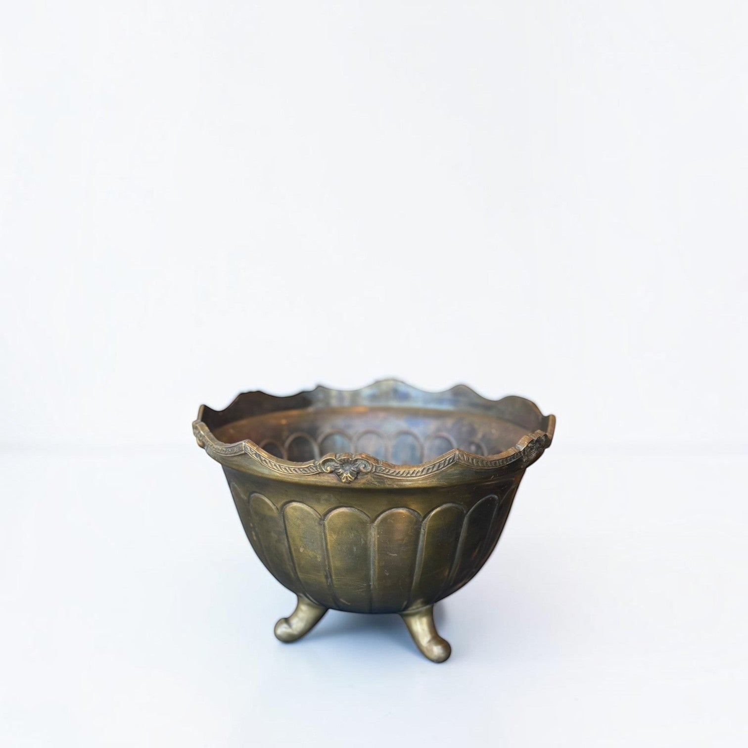 Her Good Eye vintage brass footed bowl with ornate scalloped rim and aged patina on a white background.