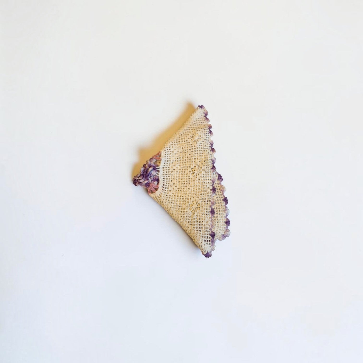 Her Good Eye vintage cream crochet doily with intricate open-weave pattern and variegated purple scalloped edge.