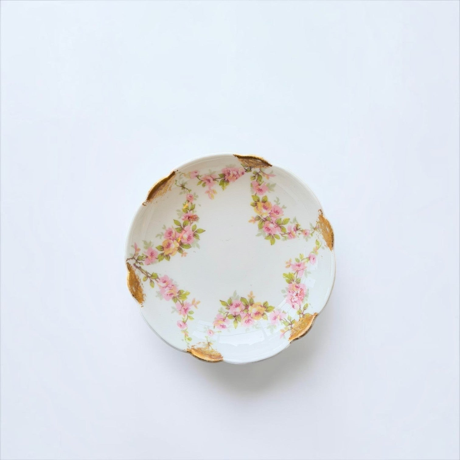 Her Good Eye vintage porcelain dish with pink and yellow floral motifs and gold-leaf scalloped edges on white background