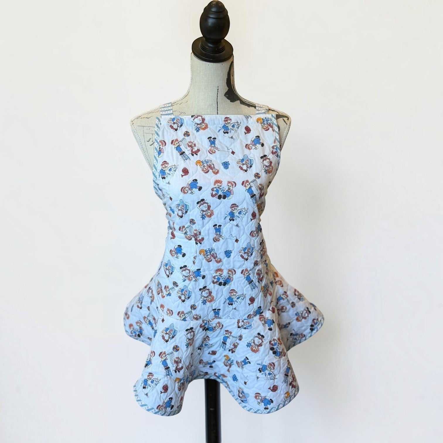 Her Good Eye vintage-inspired light blue quilted kitchen apron with a playful novelty print of children playing.