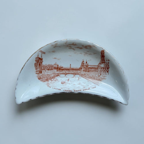 Her Good Eye crescent-shaped porcelain dish with sepia illustration of The Lagoon Looking South World's Fair, gold trim.